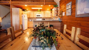 A wooden interior with a dining table set for four, a kitchen area with wooden cabinets, a microwave, and a refrigerator. - Haus Crisler (Breckenridge)