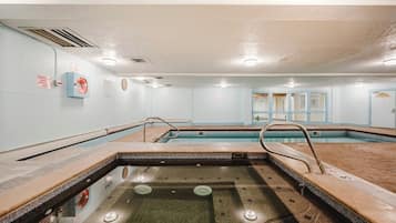 A swimming pool with a tiled deck, a diving board, and a lifeguard chair.