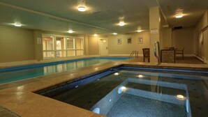 Une piscine intérieure à l’eau claire, avec des murs carrelés et des luminaires au plafond.