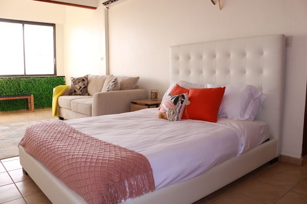 A bedroom with a large bed, a sofa, a small table, and a green wall.