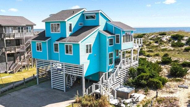 Une maison bleue à deux étages, dotée d’un balcon, d’un jacuzzi et offrant une vue sur l’océan.