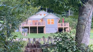 Eine rustikale Holzhütte mit einer Holzterrasse, umgeben von dichtem Grün.