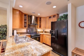 Enjoy cooking in this well-equipped kitchen with a stainless steel sink, refrigerator, and stove.