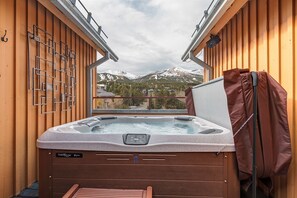 Relax in the hot tub on the cabin's balcony with a breathtaking view of snow-capped mountains.