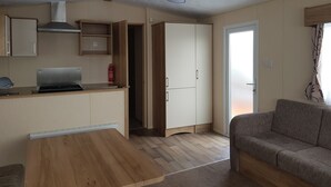A compact living space with a kitchenette, a sofa, and a wardrobe. - 8 Berth Caravan with Spacious enclosed garden (Brean)