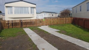A mobile home with a fenced yard and a paved walkway. - 8 Berth Caravan with Spacious enclosed garden (Brean)