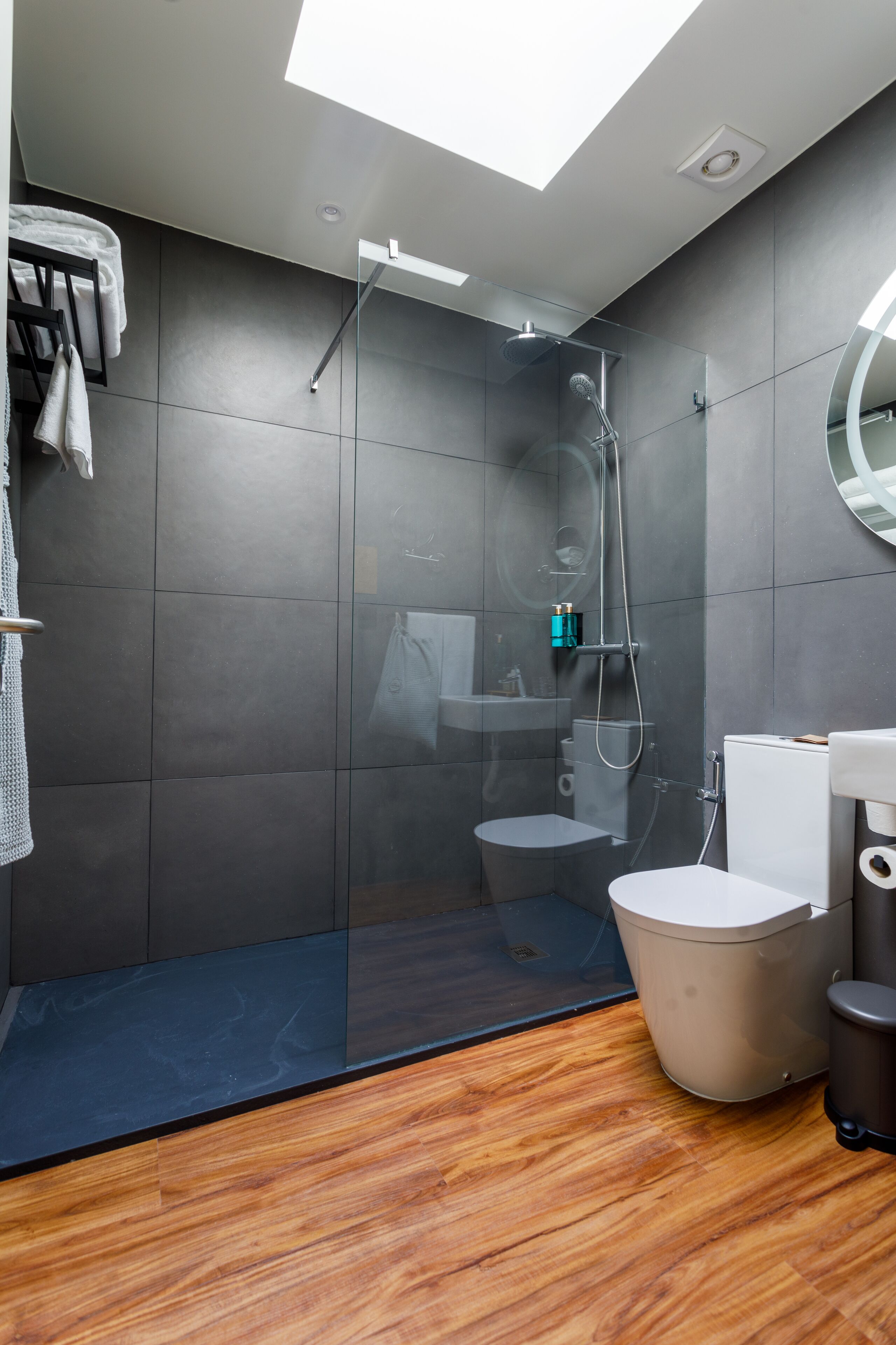 A modern bathroom with a glass-enclosed shower, a toilet, and a sink.