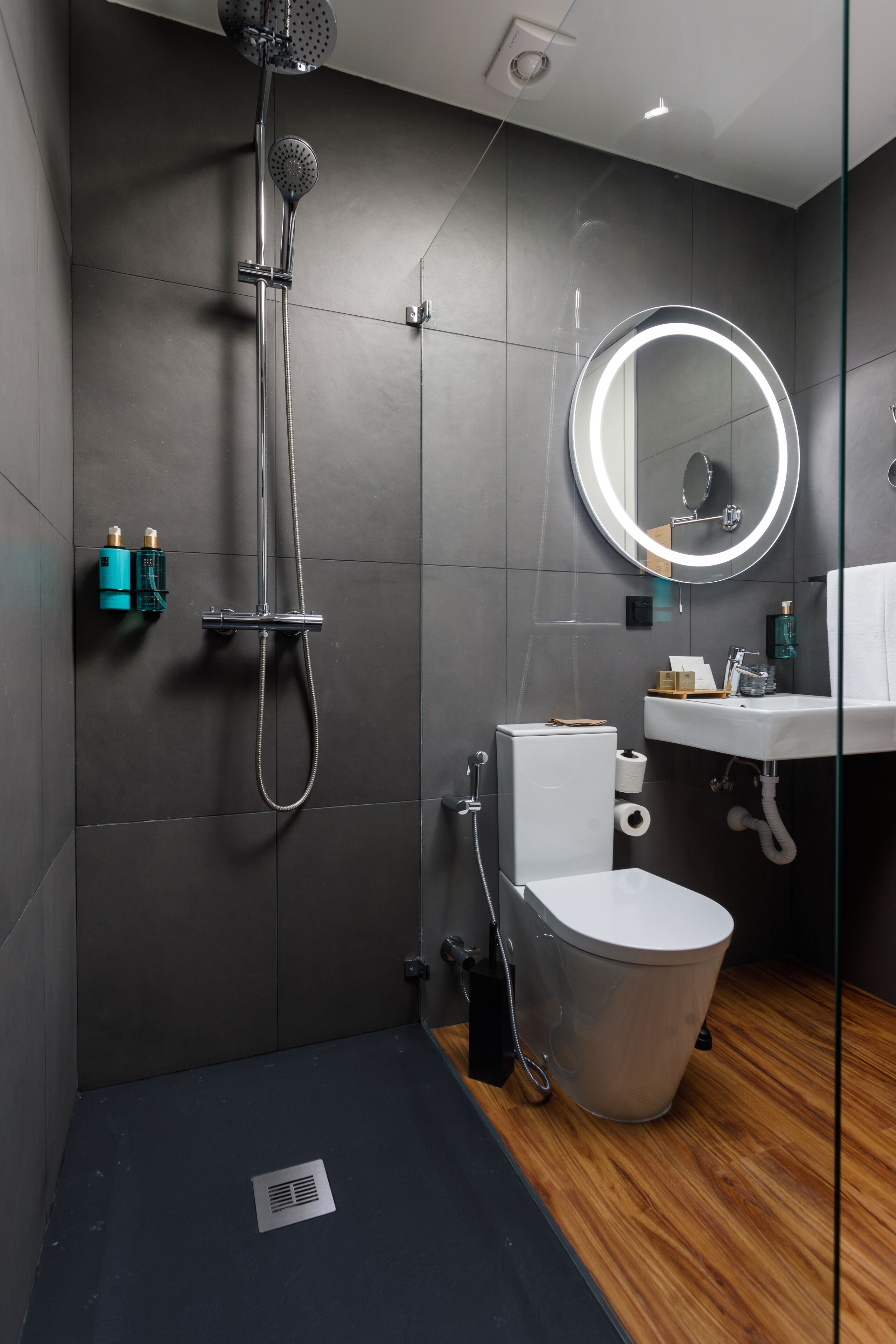 Een moderne badkamer met douche, toilet, wastafel en een spiegel met verlichting.