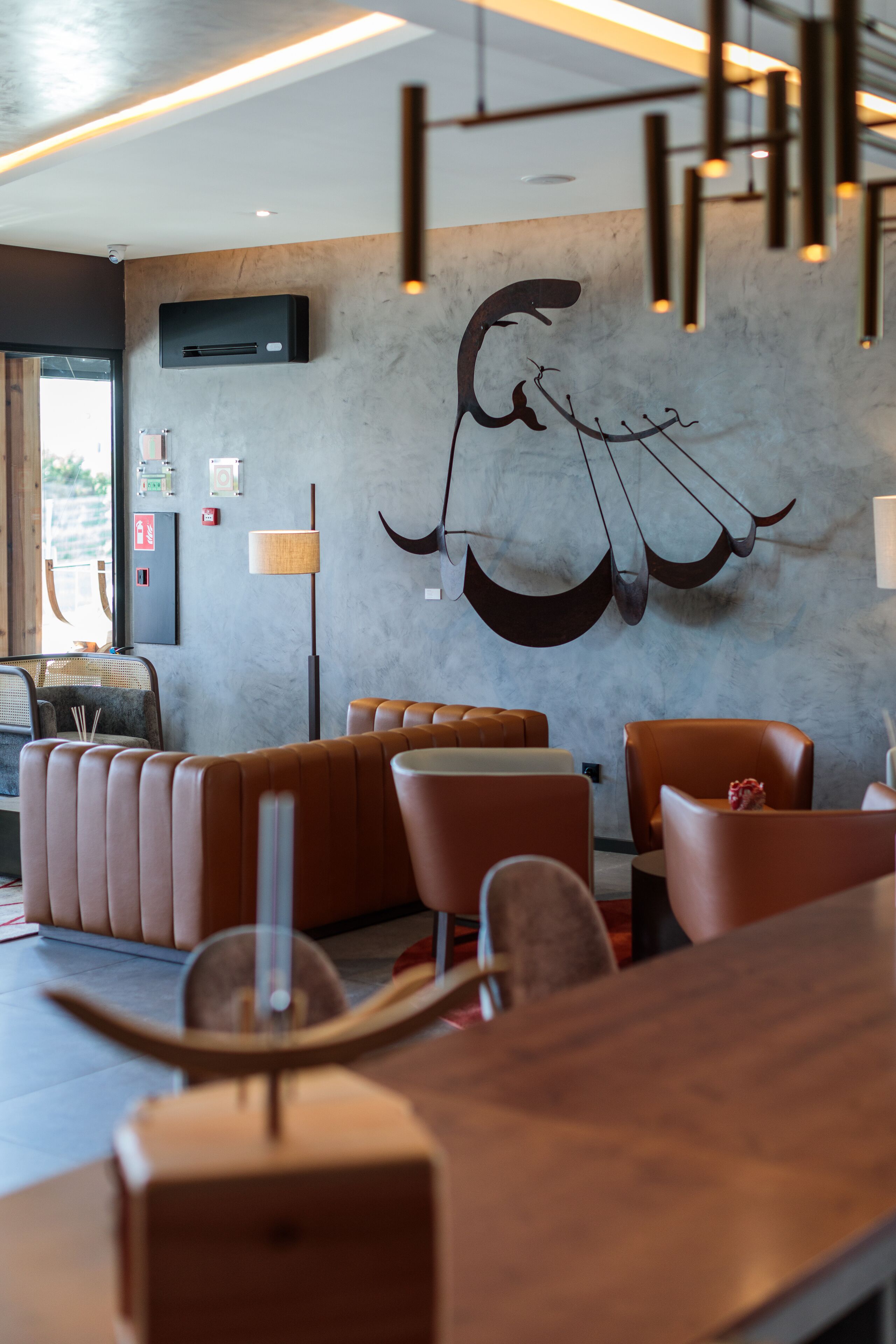 Ein modernes Restaurant-Interieur mit Ledersitzmöbeln, einer Holzbar und einer Wanddekoration.