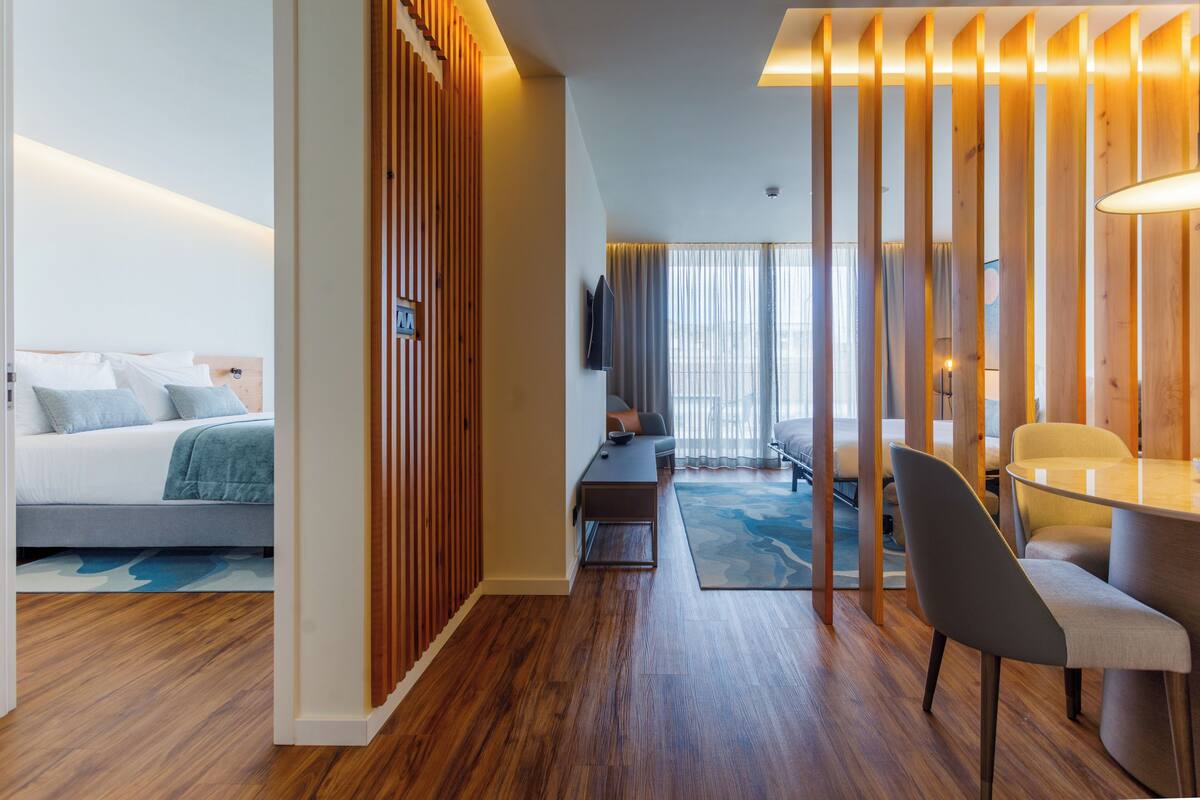A modern hotel room with a bed, a desk, a chair, and a TV.