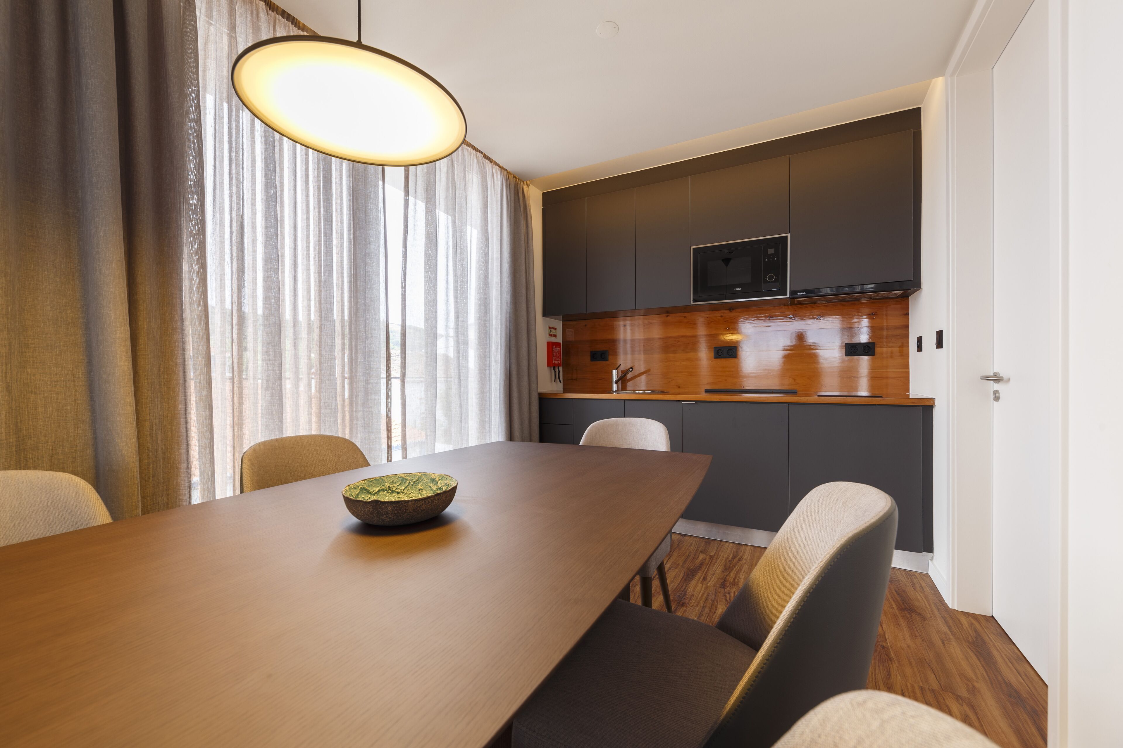 A modern kitchen with dark cabinets, a wooden countertop, and a built-in microwave.