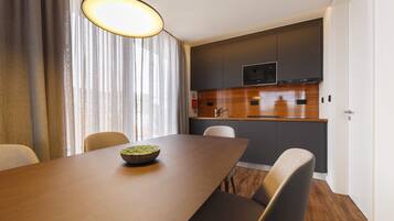 A modern kitchen with dark cabinets, a wooden countertop, and a built-in microwave.