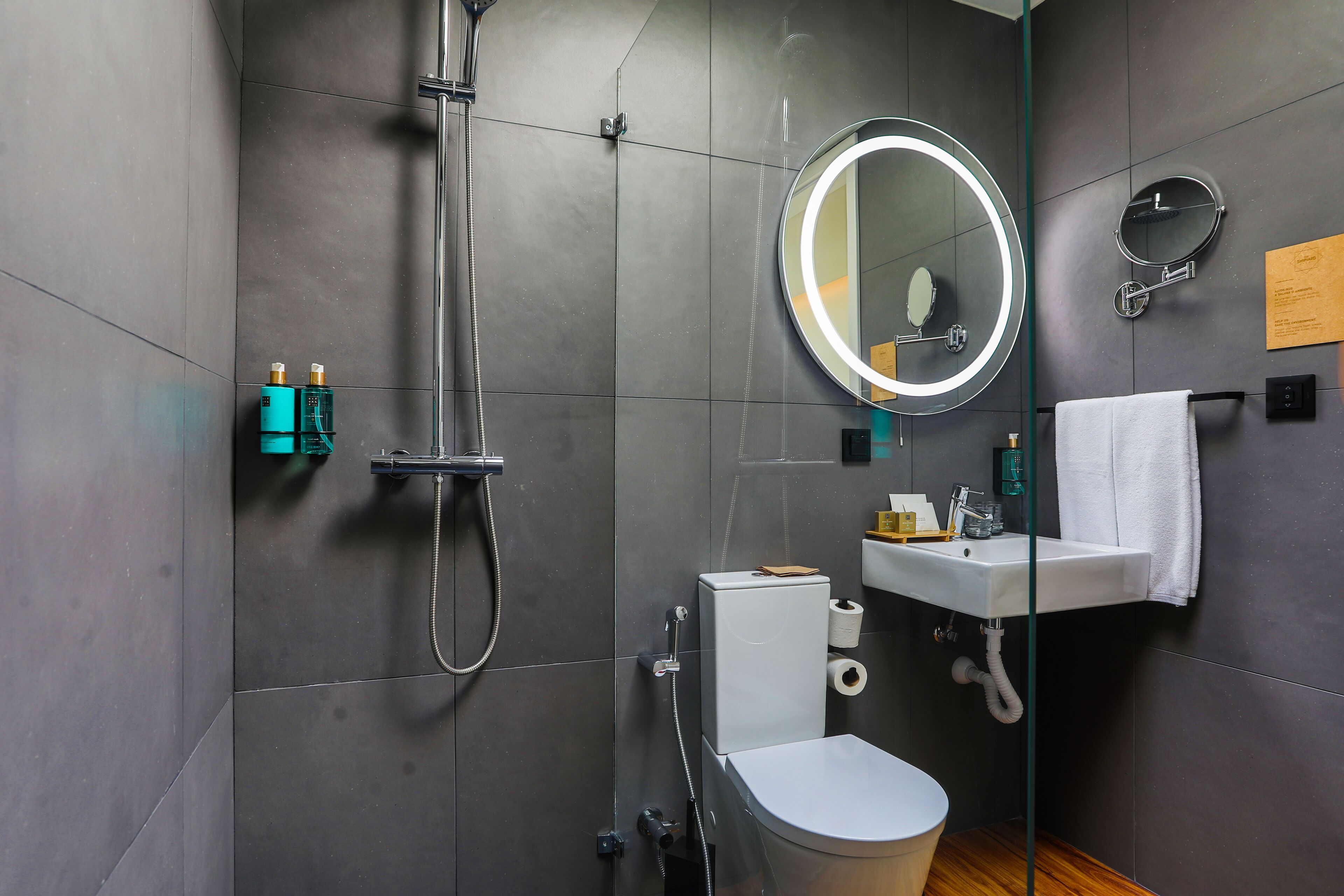 Et moderne badeværelse med bruser, toilet, vask og to spejle.