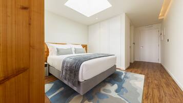 Un dormitorio con cama, tragaluz, armario y puerta.