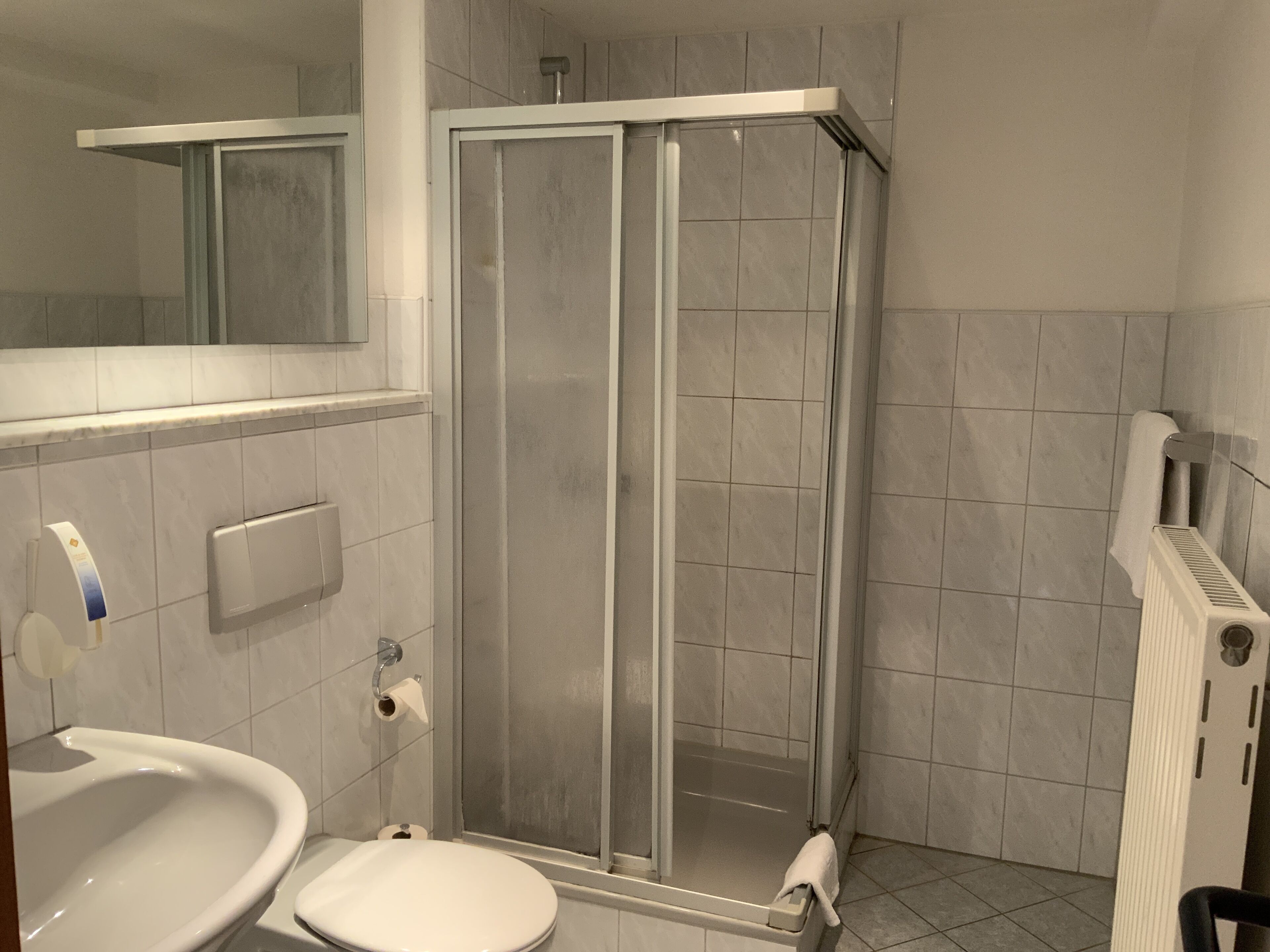 Un baño con inodoro, lavamanos y cabina de ducha.