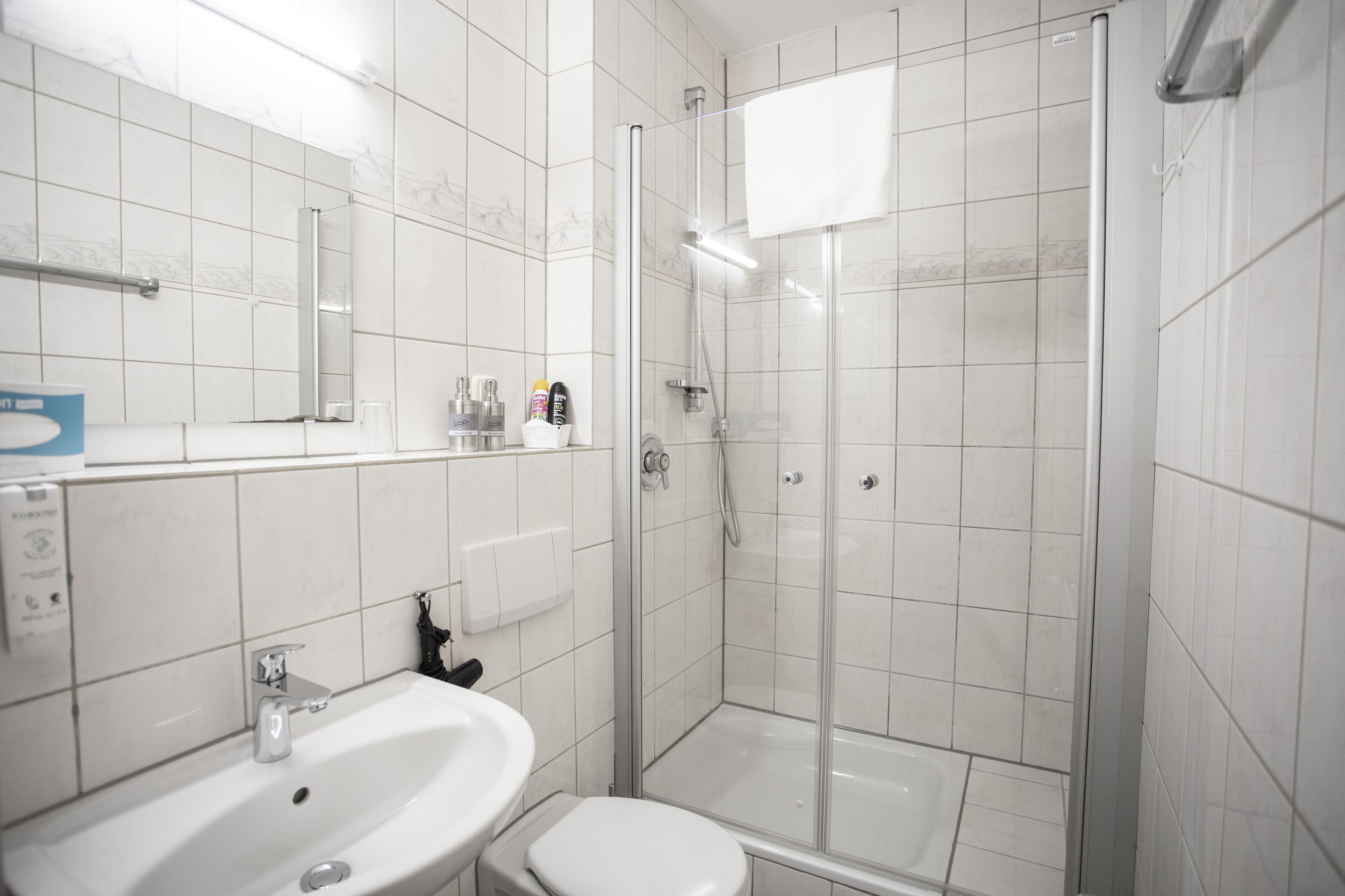 Een moderne badkamer met een witte wastafel, toilet en douchecabine met glazen wanden.