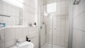 Een moderne badkamer met een witte wastafel, toilet en douchecabine met glazen wanden.