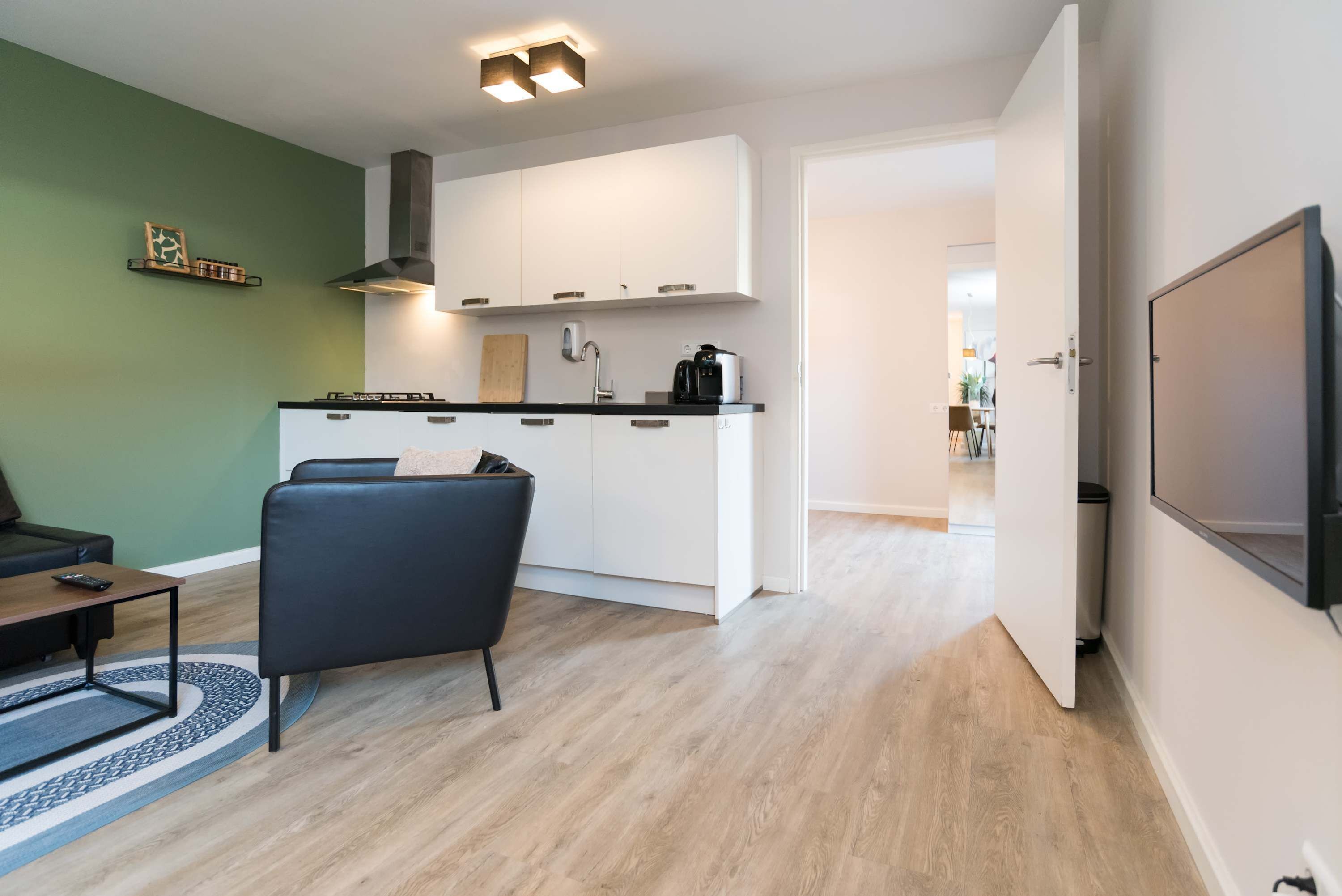 A modern kitchen with white cabinets, a black chair, and a dining table.