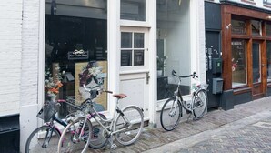 Ein weißes Gebäude mit einem Laden und zwei draußen abgestellten Fahrrädern auf einem Backsteinpflaster.