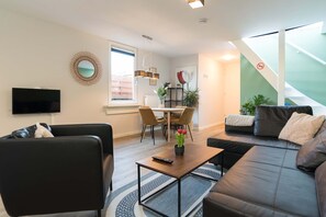 Un salon moderne comprenant un canapé, une table basse, un téléviseur et un coin repas avec des chaises et une table.