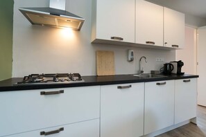 Een koelkast, een vaatwasser, kookgerei, borden en bestek