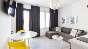 Una sala de estar moderna con una mesa redonda blanca, sillas amarillas, un sofá gris y una mesa de centro blanca.