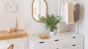 Un baño minimalista con tocador de madera, espejo, reloj, planta y perchero.
