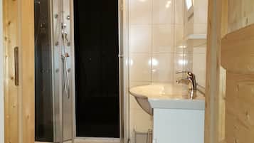 A compact bathroom with a glass-enclosed shower, a white sink, and a toilet.