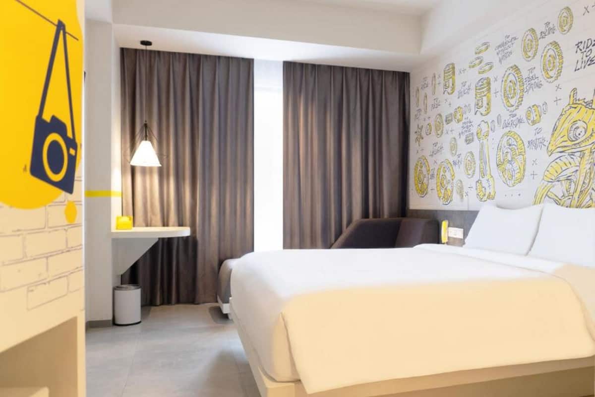 A hotel room with a bed, a desk, and a lamp.
