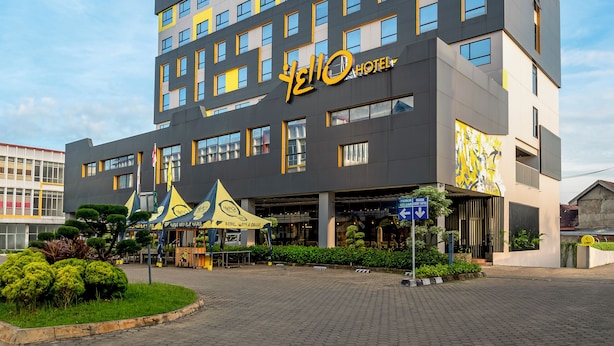 A modern hotel building with a prominent yellow and black color scheme, multiple floors, and a clear sky in the background. - YELLO Hotel Jambi (Jambi)