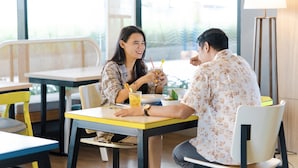 A dining area with tables and chairs, a lamp, and a view of the outdoors. - YELLO Hotel Jambi (Jambi)