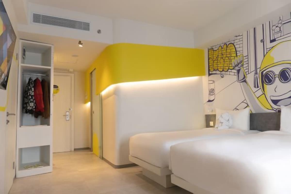 A hotel room with a bed, a wardrobe, and a mural on the wall.