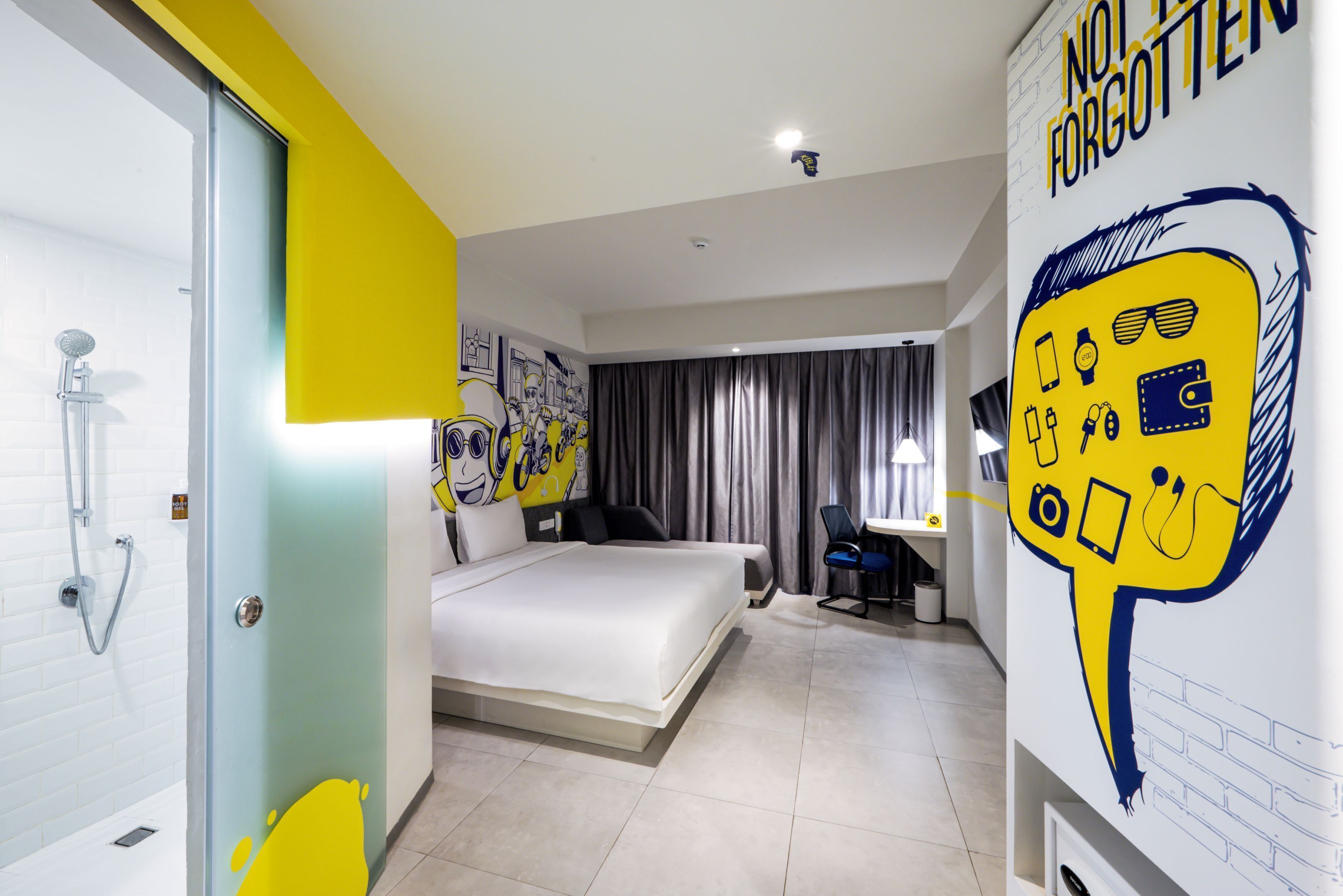 A modern hotel room with a bed, a desk, and a shower.