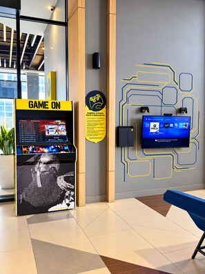 A gaming station with a monitor displaying FIFA 23, a gaming console, and a sign with gaming rules. - YELLO Hotel Jambi (Jambi)