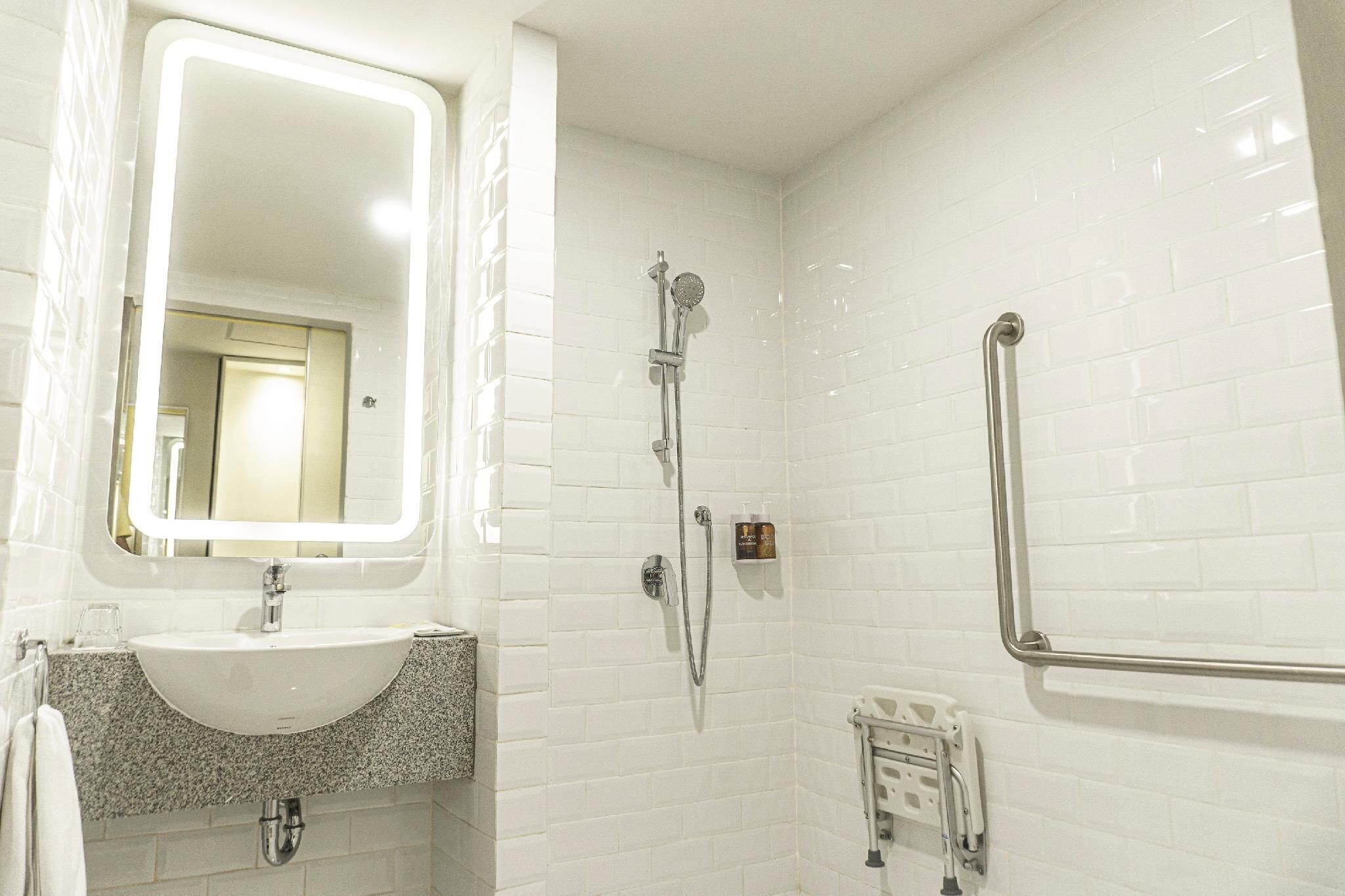 Une salle de bain avec un lavabo blanc, un miroir et une douche.