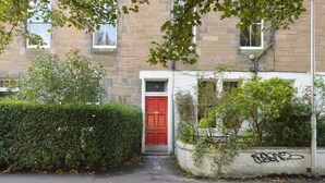A narrow alleyway with a red door, a hedge, and a building with a stone facade. - Home by The Meadows, close to City Centre (Edinburgh)