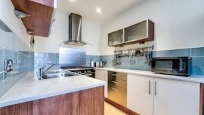 A modern kitchen with a central island, stainless steel appliances, and blue-tiled backsplash. - Home by The Meadows, close to City Centre (Edinburgh)