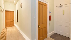 A hallway with wooden doors, a fire extinguisher, and a clock on the wall. - Home by The Meadows, close to City Centre (Edinburgh)