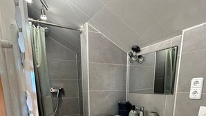 A modern bathroom with a shower, a sink with a mirror, and a toilet. - Vacation apartment for 2 persons Hopferau (Hopferau)