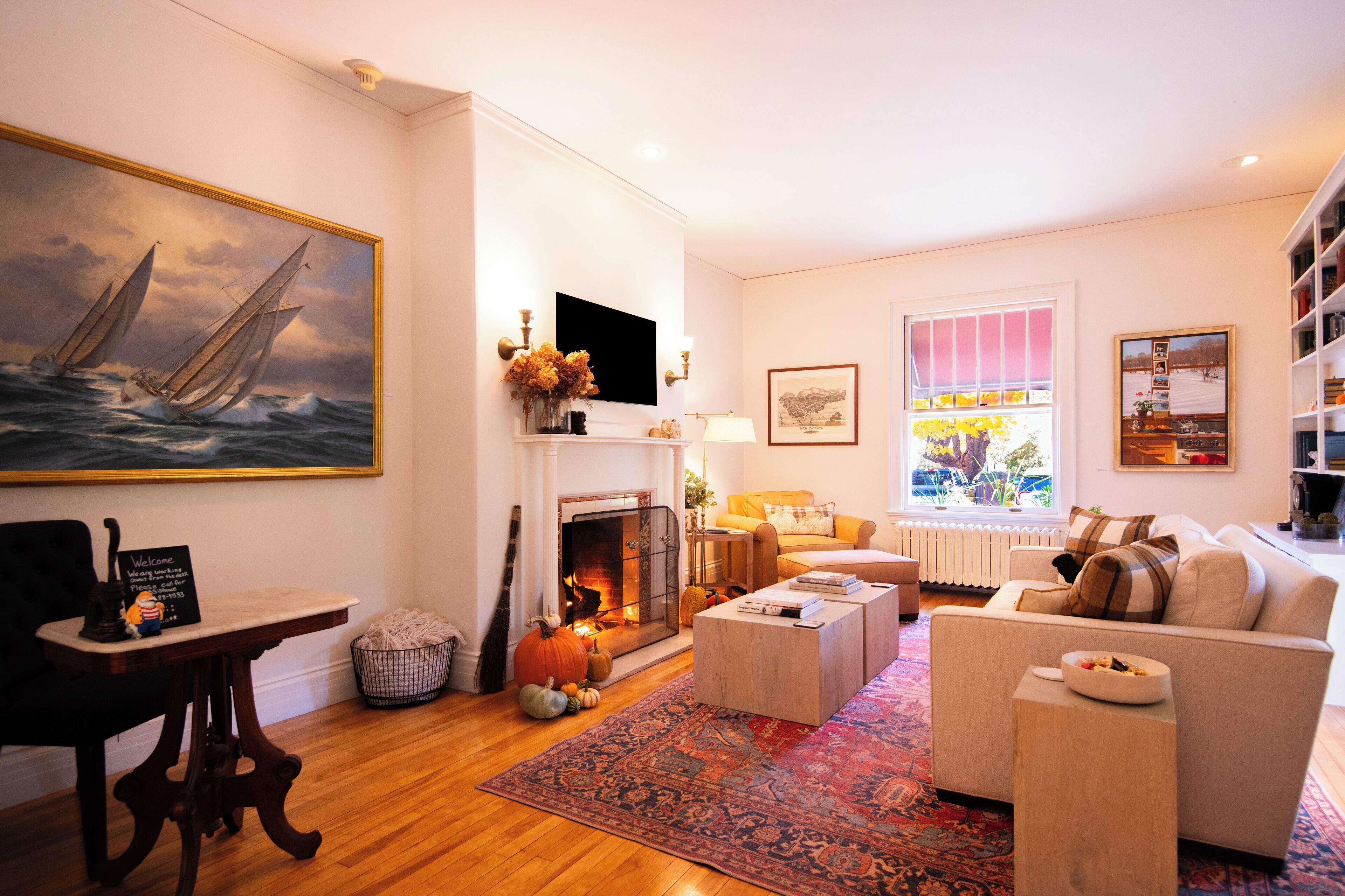 Un salon chaleureux avec une cheminée, un canapé, une table basse et un tableau représentant un voilier.