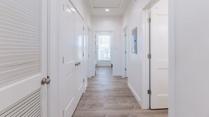Un couloir avec des portes blanches et un plancher en bois.