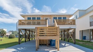 Une maison à deux étages avec une terrasse en bois à l’avant, un toit en métal et le numéro 339 sur le côté.