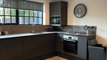 A modern kitchen with dark cabinetry, a large window, and a built-in oven.