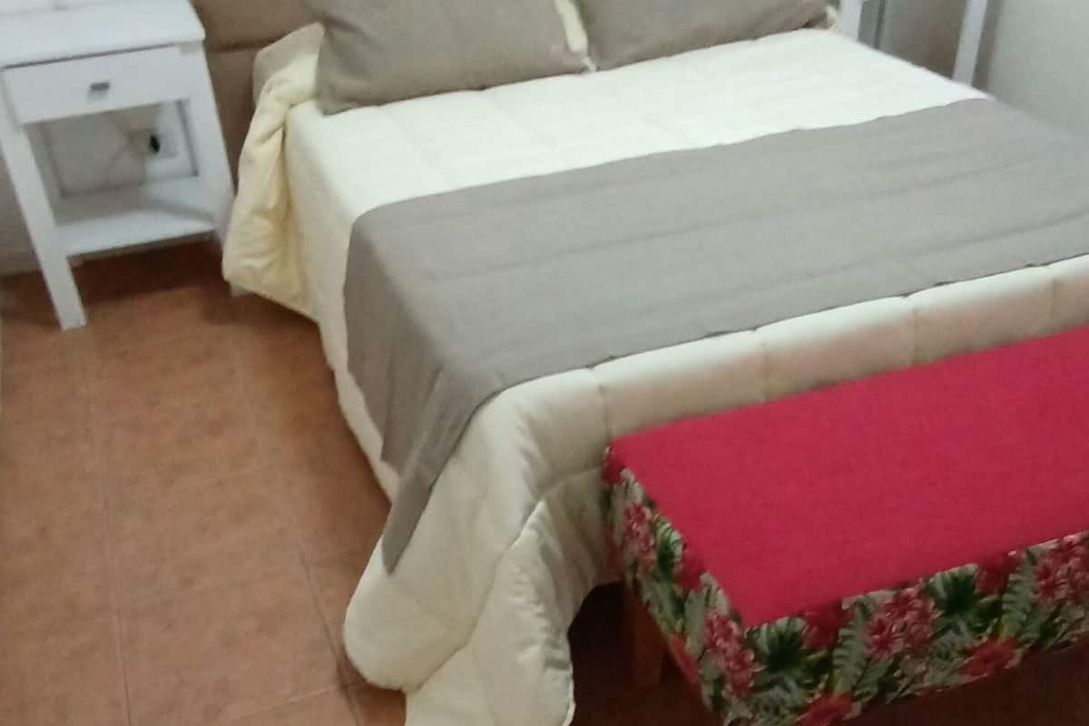 A bedroom with a bed, nightstands, and a bench.