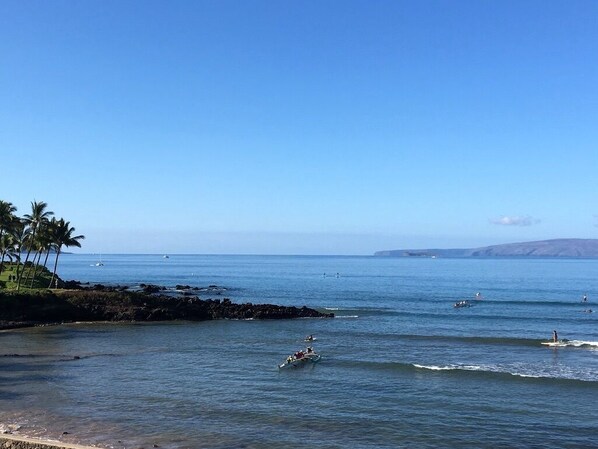 Un paysage côtier avec une mer calme, une côte rocheuse et un ciel dégagé.