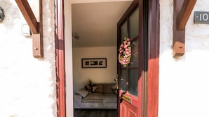 Un passage donnant sur une pièce avec un plancher en bois, un canapé et une porte portant une plaque avec un numéro.