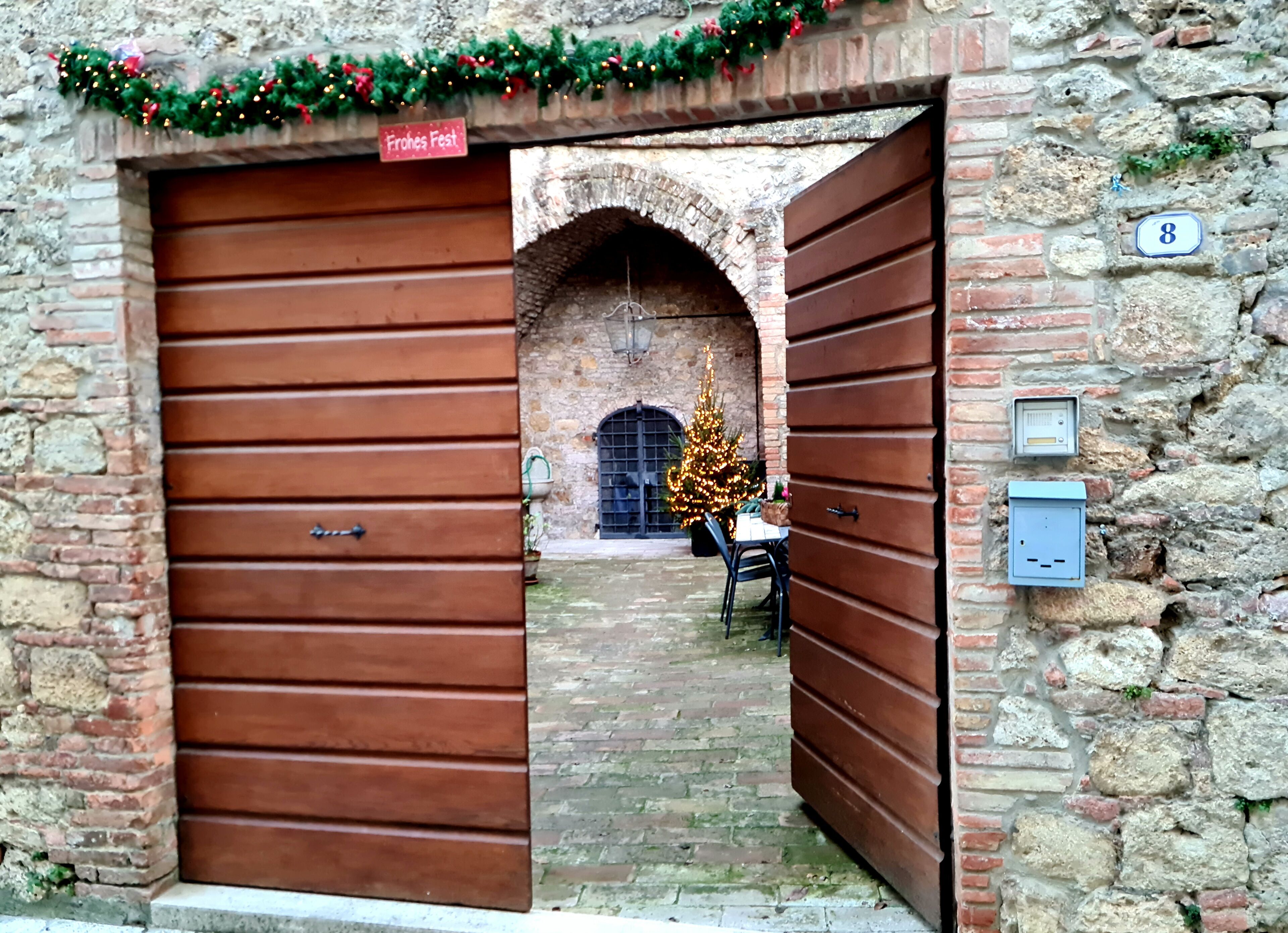 Un bâtiment en pierre doté de deux grandes portes en bois, d’un sapin de Noël et d’une enseigne sur laquelle on peut lire « Frohes Fest ».