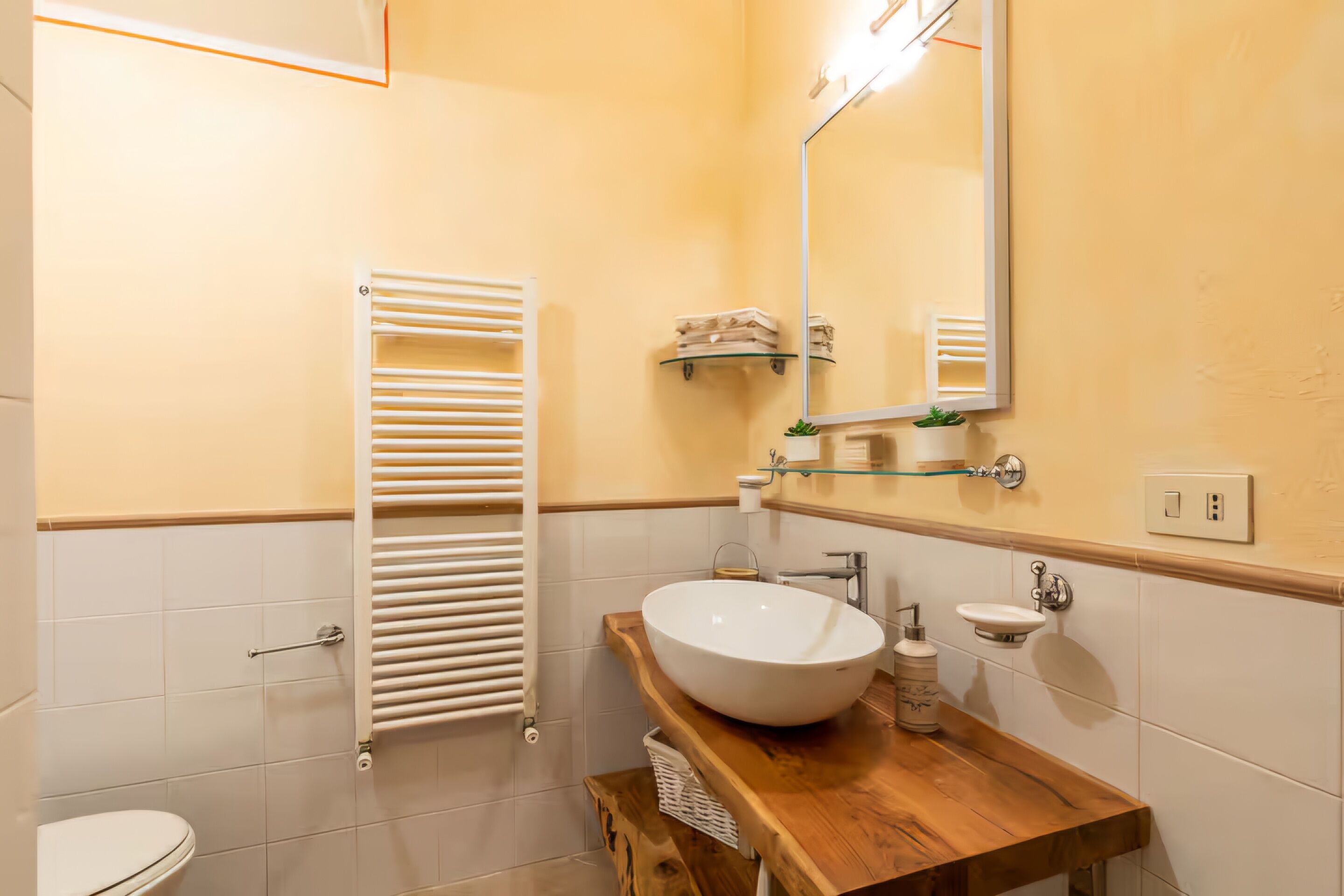 Une salle de bain avec un meuble-lavabo en bois, un lavabo blanc, un porte-serviettes et un miroir.