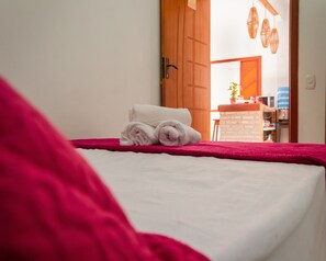 Quarto de hotel com uma cama, uma porta de madeira e vista para a cozinha.