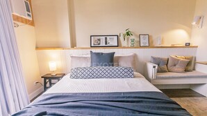 A hotel room with a bed, bedside table, lamp, and a small seating area with cushions. - Astonishing Home Office Balcony Cebu CBD Furnished (Cebu City)